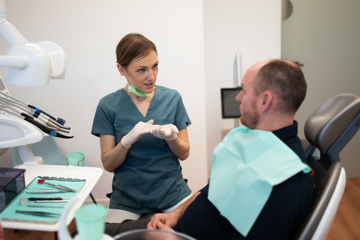 Eine Zahnärztin spricht mit einem Patienten im Behandlungszimmer