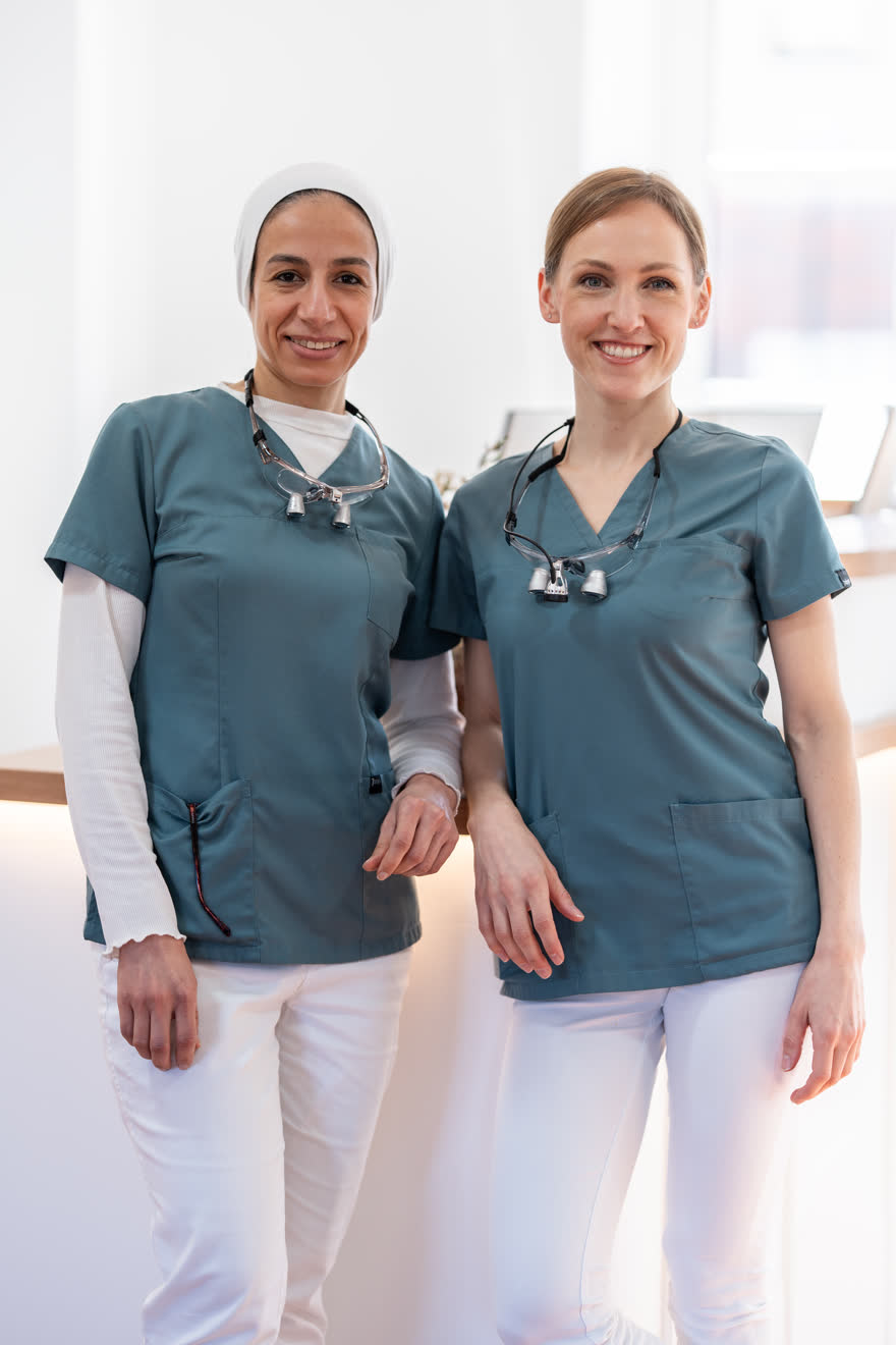 Manar Maze und Dr. Annika Jerg in dunkelgrüner Praxiskleidung am Empfang